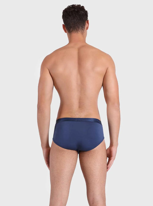 Man wearing a navy blue swim brief on a light gray background